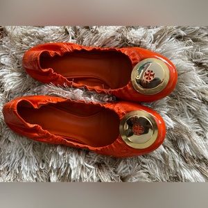 Tory Burch orange patent leather ballet slippers with gold buckle.